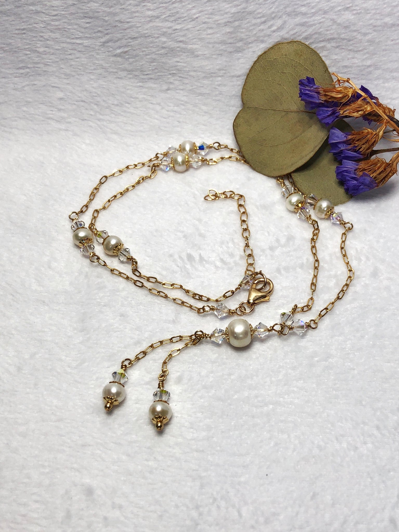 Freshwater pearl Swarovski crystal gold filled necklace laying flat on a white background